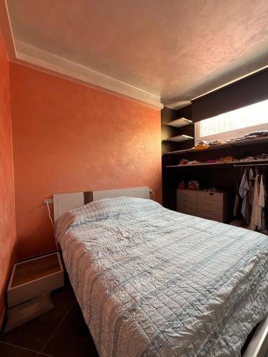 ein Schlafzimmer mit einem Bett mit einer orangefarbenen Wand in der Unterkunft Appartamento clarissa in Alassio
