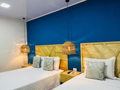 2 camas en una habitación con paredes azules en WE Hotel, La Lima en La Lima