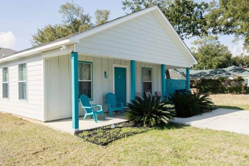 una pequeña casa blanca con sillas azules en el porche en Happy Beach House in Biloxi en Biloxi