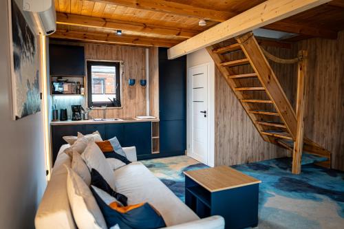 a living room with a couch and a staircase at GooseHaus z prywatną sauną i jacuzzi in Gąski