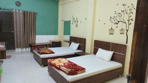 a room with two beds and a tree on the wall at HOTEL GS MARRIAGE GARDEN , KARELI in Karelī