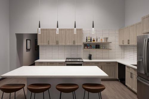 a kitchen with a white counter top and brown stools at Trilith Guesthouse, Fayetteville, GA, a Tribute Portfolio Hotel in Fayetteville