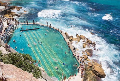 Leute schwimmen in einem Pool neben dem Meer in der Unterkunft Bronte Boho Chic near Ocean with Parking in Sydney