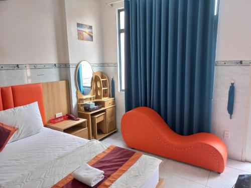 a bedroom with a bed and a red chair next to a window at Khách Sạn Nguyên Trung in Ho Chi Minh City