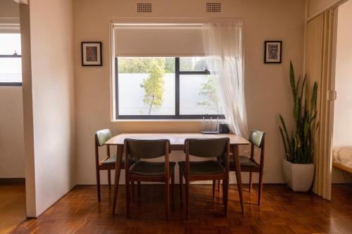 mesa de comedor con sillas y ventana en Light-Filled Paddington Studio with Parking en Sídney
