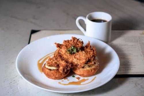 a plate with a piece of fried food and a cup of coffee at The Ballantyne, a Luxury Collection Hotel, Charlotte in Charlotte