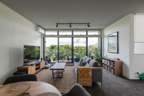 a living room filled with furniture and a large window at Treetops Camperdown Inner City Bliss w Parking in Sydney