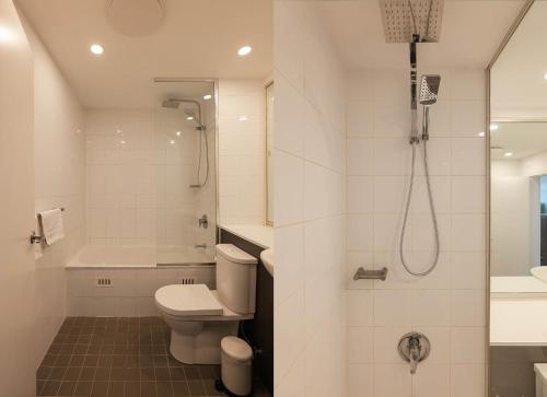 a white bathroom with a shower and a toilet at Treetops Camperdown Inner City Bliss w Parking in Sydney