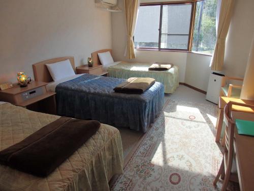 a hotel room with three beds and a window at Forest Villa YUMESUZU the Closest Accommodation to the Metasequoia Tree-lined Avenue in Takashima