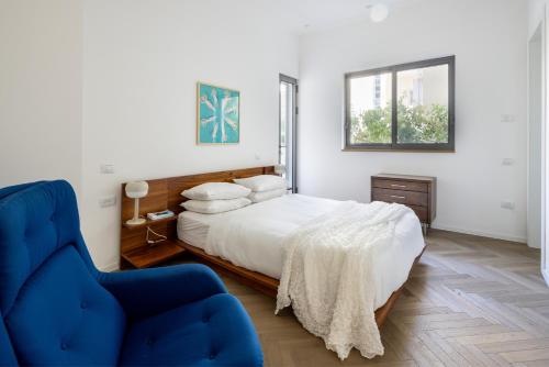 um quarto com uma cama e uma cadeira azul em Heart of Tel Aviv Garden Oasis by Sea N' Rent em Tel Aviv