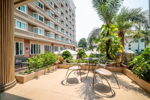 un patio con mesa y sillas y un edificio en J A Plus Hotel en Pattaya Central