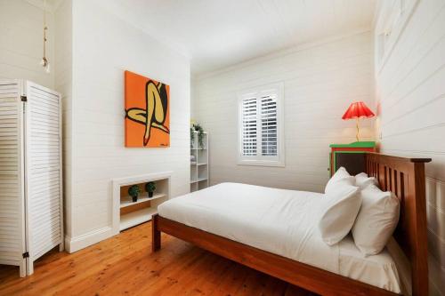 a white bedroom with a bed and a fireplace at Thyme Cottage Warrnambool in Warrnambool