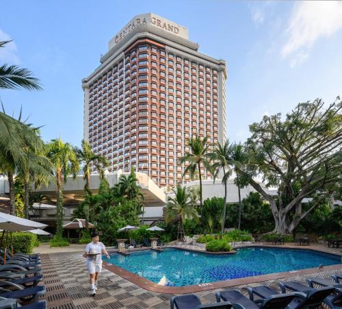 a man walks by a hotel with a large building at Centara Grand at Central Plaza Ladprao Bangkok in Bangkok