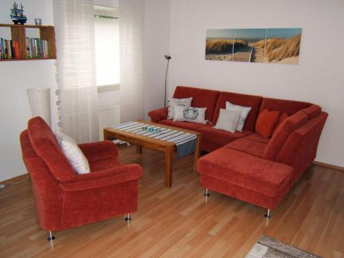 salon z czerwoną kanapą i 2 krzesłami w obiekcie Holiday apartment with a garden w mieście Horumersiel