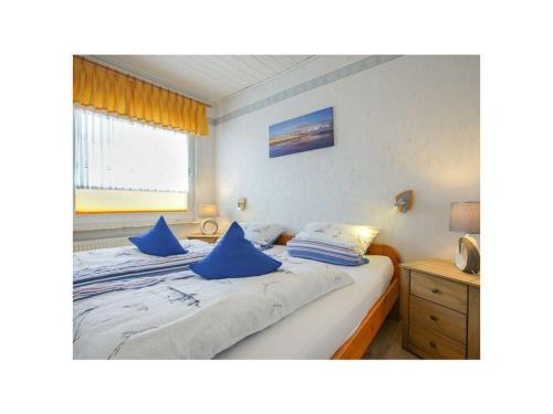 a bedroom with a bed with blue pillows on it at Holiday home - Beckmann-Visser 3 in Borkum