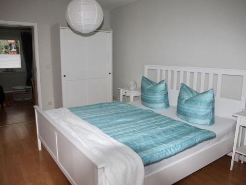 uma cama branca com almofadas azuis num quarto em Snug holiday home with garden em Timmendorfer Strand