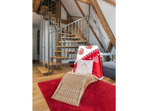 a living room with a red rug and stairs at Romantic maisonette in Schonach