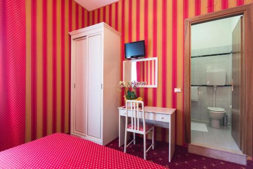 a room with a desk and a toilet and red stripes at Hotel Messner in Venice