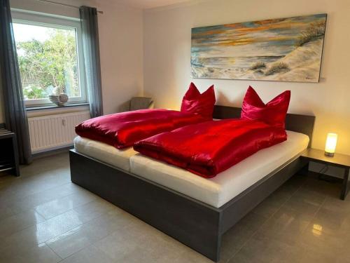 1 cama con almohadas rojas en el dormitorio en Lovely holiday home with sauna, en Hooksiel