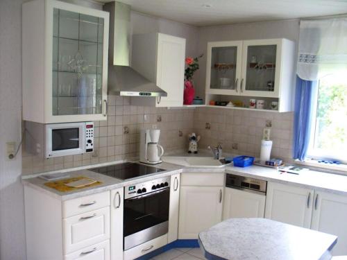 a kitchen with white cabinets and a sink at Rose ambience Modern retreat in Bad Langensalza