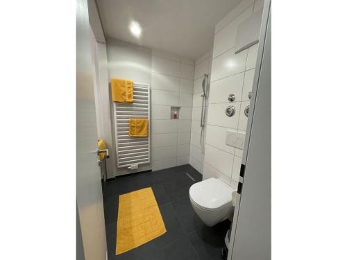 a bathroom with a white toilet and a yellow rug at Hochgrat view in Steibis, Haus Akelei in Steibis