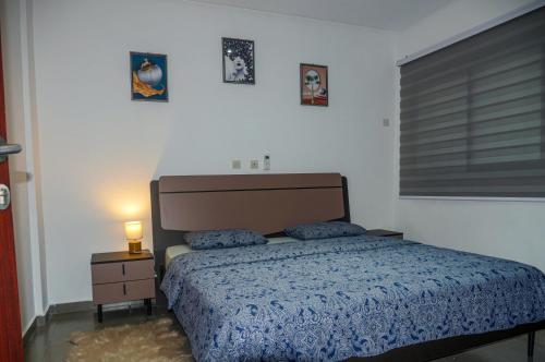 1 dormitorio con 1 cama y mesita de noche con lámpara en RESIDENCE MH SERVICES Abidjan en Abiyán