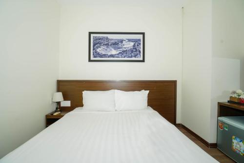 a bedroom with a white bed with a wooden headboard at Central Hotel & Spa Danang in Da Nang