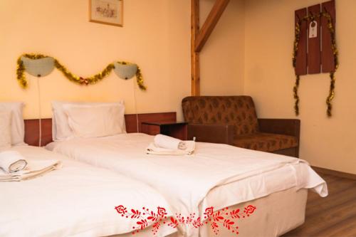 two beds in a room with a chair at Pension Tip-Top in Târgu-Mureş