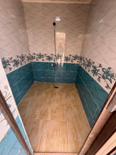 y baño con ducha de azulejos azules. en شاليه البحر الميت الرامة-Deadsea, en Al Rama