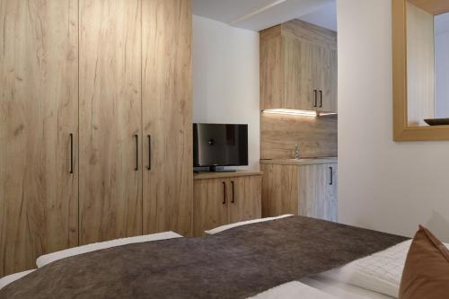 a bedroom with wooden cabinets and a tv on the wall at Aparthotel Familiaris - Family Apartments - Pools & Spa in Dolomites in Valdaora