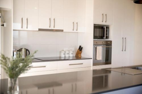 a kitchen with white cabinets and a counter top at Couples Getaway on Bruny Island in Alonnah