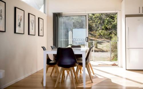 a dining room with a white table and black chairs at Couples Getaway on Bruny Island in Alonnah