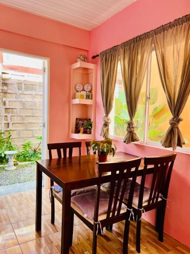a dining room with pink walls and a table and chairs at Cara Transient house in San Pablo