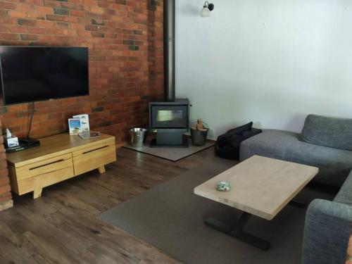 a living room with a couch and a tv at Close to Town and Very Private in Myrtleford