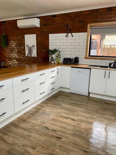 a kitchen with white cabinets and a wooden floor at Close to Town and Very Private in Myrtleford