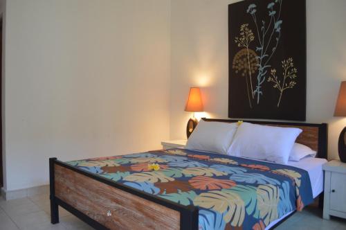 a bedroom with a bed with a colorful comforter at Little Pond Homestay in Sanur