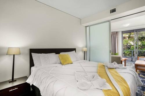 1 dormitorio con 1 cama blanca grande y toallas amarillas. en Absolute Waterfront - Enjoy Exceptional Lifestyle, en Cairns