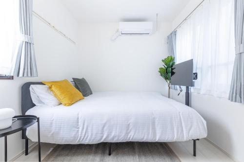 a white bedroom with a bed with a yellow pillow at 67 Apt Koenji Tokyo in Tokyo