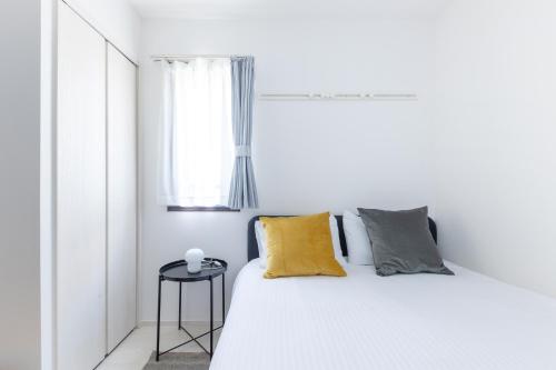 a white bedroom with a white bed and a window at 67 Apt Koenji Tokyo in Tokyo