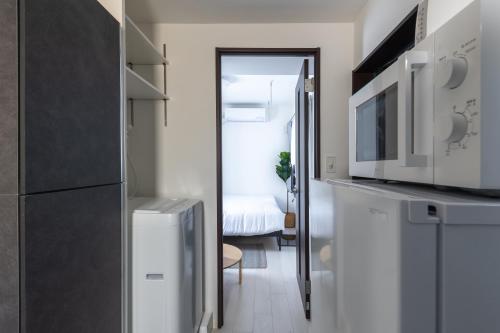 a kitchen with a microwave and a room with a bed at 67 Apt Koenji Tokyo in Tokyo