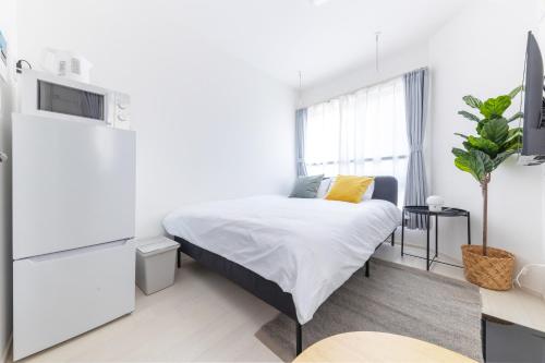 um quarto branco com uma cama e uma televisão em 67Hotel Koenji Tokyo em Tóquio