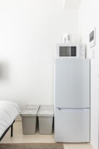 a white refrigerator in a bedroom with two trash cans at 67 Apt Koenji Tokyo in Tokyo