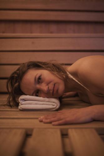 a woman laying on a towel in a sauna at Aparthotel Familiaris - Family Apartments - Pools & Spa in Dolomites in Valdaora