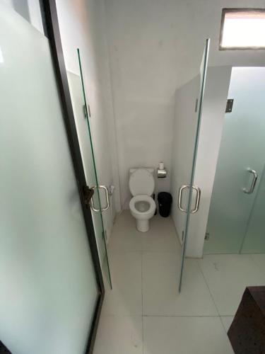 a bathroom with a toilet and a glass door at Mangga Wangga Living in Uluwatu