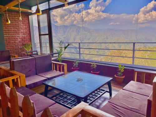 um quarto com uma mesa e cadeiras e uma grande janela em The Pine Woods - A Four Star Luxury Resort in Mussoorie em Mussoorie