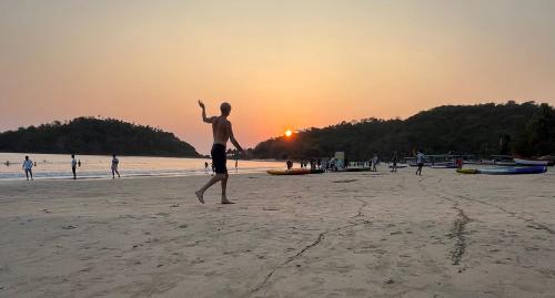a man standing on the beach playing with a frisbee at Fernandes Bar and Restaurant in Canacona