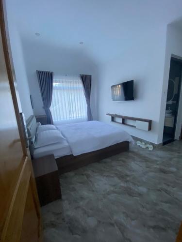 a bedroom with a large white bed and a window at Ánh Tiên Hotel Da Lat in Da Lat