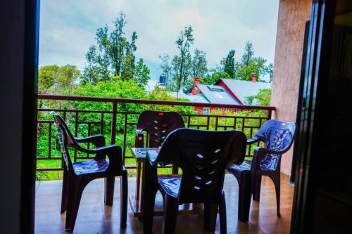 four chairs and a table on a balcony with a view at HOTEL SAMRUDDHI in Panchgani