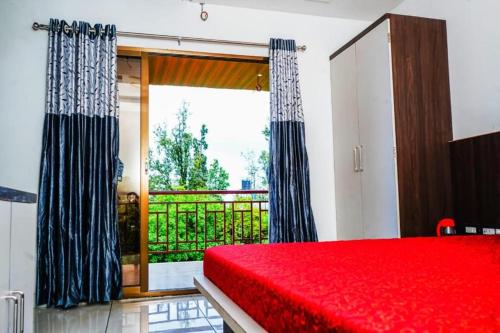 a bedroom with a red bed and a large window at HOTEL SAMRUDDHI in Panchgani