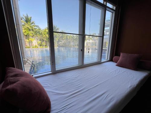 Bett in einem Zimmer mit einem großen Fenster in der Unterkunft Hua Hin Blue Lagoon-Pool Access in Cha-am